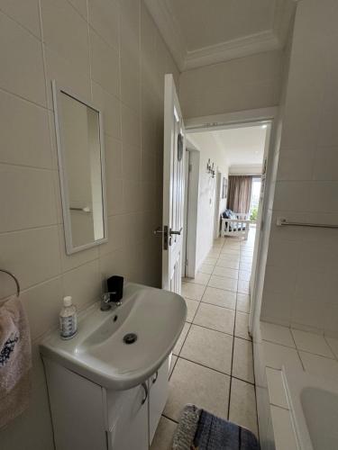 a bathroom with a sink and a tub and a mirror at Mangrove Beach Estate Boboyi in Port Shepstone
