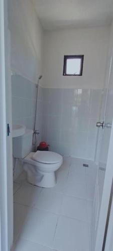 a white bathroom with a toilet and a window at Camotes Hostel Resort Fan Rooms in San Francisco