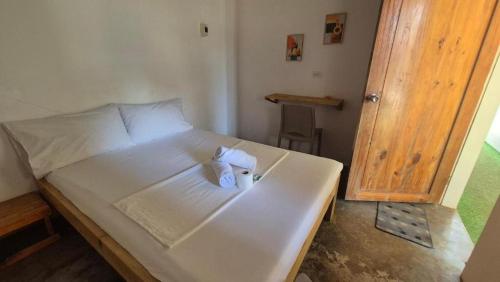 a white bed with two towels on top of it at Camotes Hostel Resort Fan Rooms in San Francisco