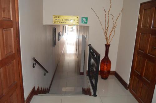 a hallway with a vase and a staircase with a sign at Lakeview Boutique Hotel & Conference Center in Benoni
