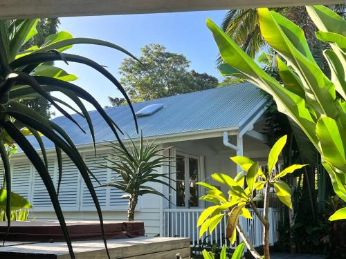 a white house with plants in front of it at Bamboo Beach House & Studio in Byron Bay