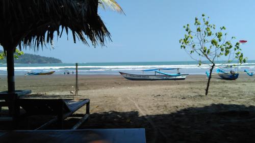 a beach with two boats on the beach at Mini Tiga Homestay in Pangandaran