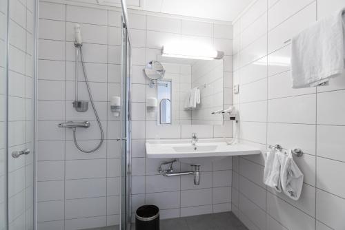 a white bathroom with a shower and a sink at Almaas Hotell Stord AS in Stord