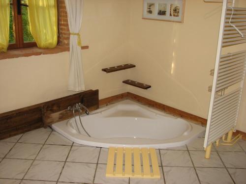 a bath tub in a bathroom with a yellow stool at Gîte les Peyrets in Montech