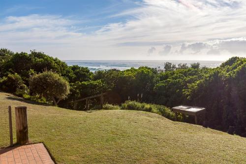 a view of the ocean from a hill with a bench at White Waves on the Beach in Hastings Point