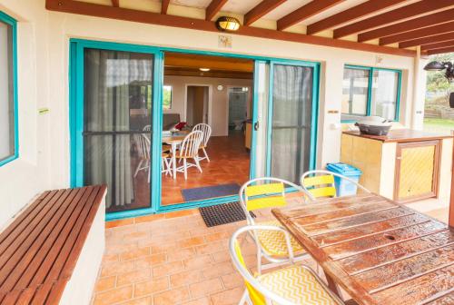 a patio with a wooden table and chairs on a house at White Waves on the Beach in Hastings Point