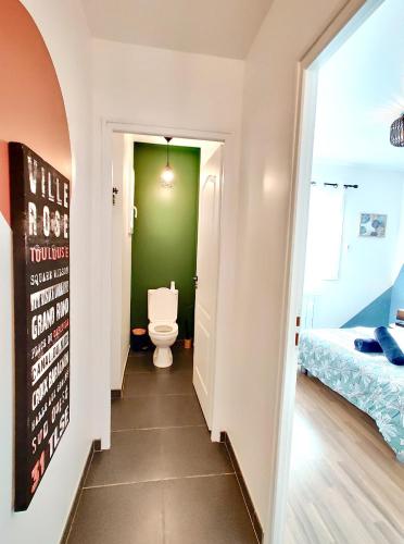 a bathroom with a toilet and a green wall at L'Écrin d'Ussat in Ussat