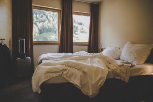 an unmade bed in a bedroom with a window at Arabella Retreat & Spa in Nauders