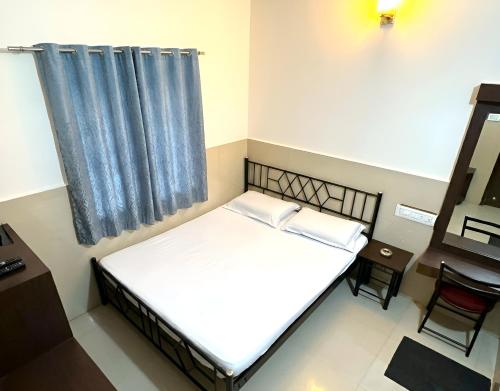 a small room with a bed and a desk at Manjusri Paradise in Bangalore