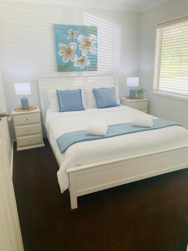 a bedroom with a large white bed with blue pillows at Bronte Lodge, Wine Country Farm Stay Hunter Valley with Games Room, Close to Town in Greta Main