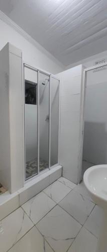 a white bathroom with a shower and a sink at Halford Backpackers, Durban in Durban