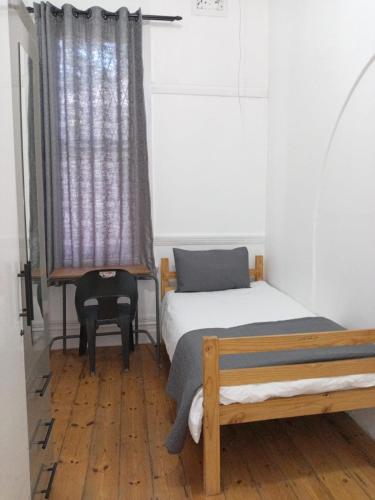 a room with two beds and a chair and a window at Halford Backpackers, Durban in Durban