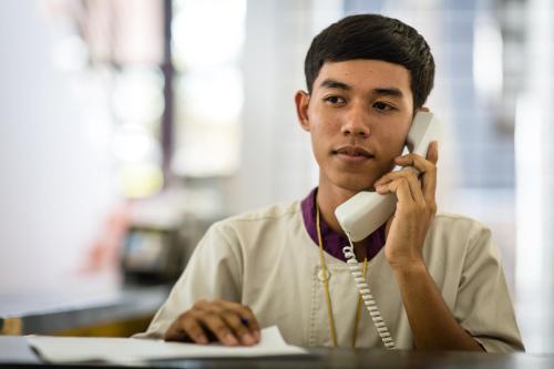 a man sitting at a desk talking on a phone at Sala Baï Hotel & Restaurant School in Siem Reap