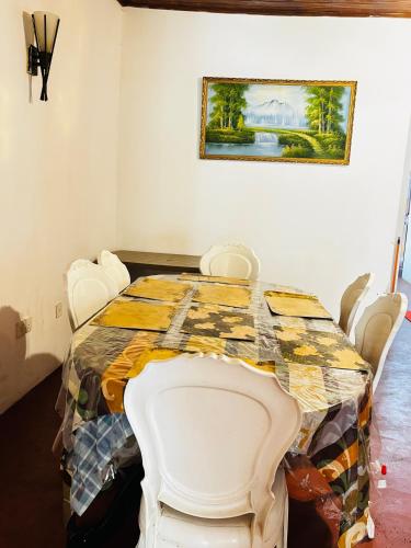 a dining room with a table with white chairs at Shellys Cottage Nuwara Eliya in Nuwara Eliya