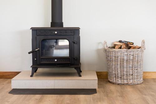 a black stove sitting in a room with a basket at Brahman Hills - Gardens, Hotel & Cottages in Nottingham Road