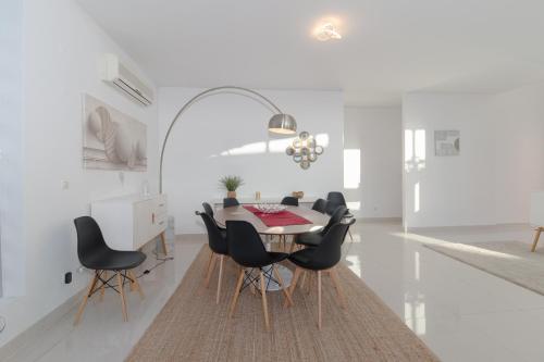 a dining room with a table and black chairs at Villa 4 Rooms, Swiming Pool Pink in Palmela
