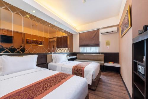 ein Hotelzimmer mit zwei Betten und einer Couch in der Unterkunft Favor Hotel Makassar City Center By LIFE in Makassar