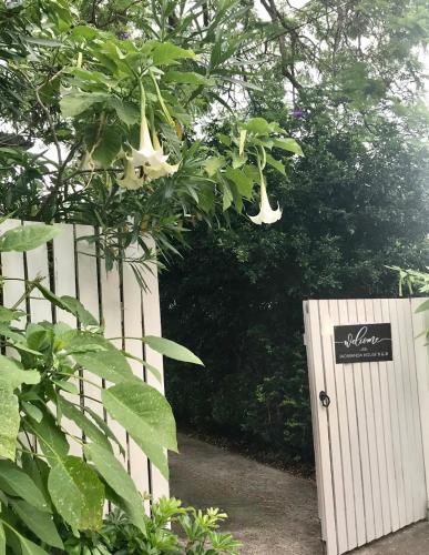 a white fence and a white door with a tree at Jacaranda House Garden Suite in Brisbane