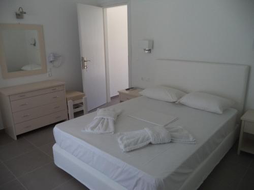 a bedroom with a white bed and a dresser and a mirror at Taxiarchis Studios in Áyios Yeóryios