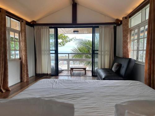 a bedroom with a bed and a couch and windows at Bang Kao Beachfront Villa in Nathon Bay