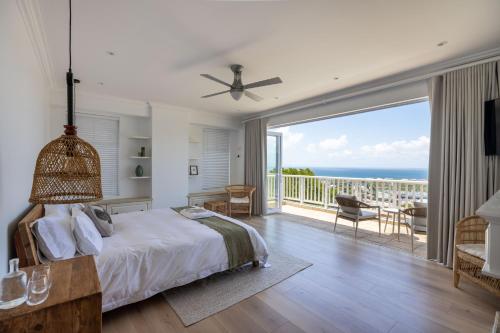 a bedroom with a bed and a balcony with the ocean at Plett Azure Guesthouse in Plettenberg Bay