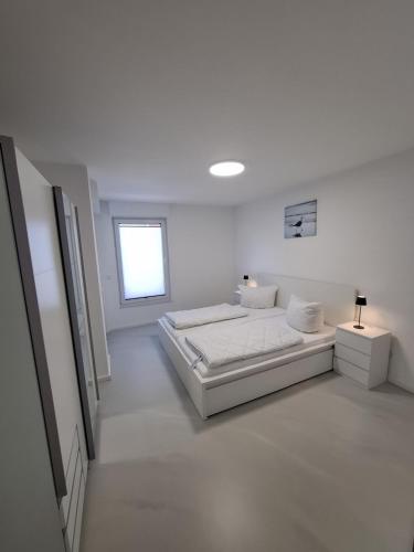 a white bedroom with a bed and a window at Wohnung in Dahme