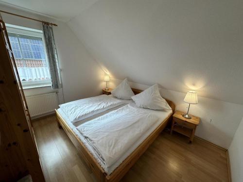 a bedroom with a bed with white sheets and a window at Fehmarn 17-5 in Fehmarn