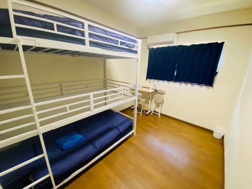 ein Schlafzimmer mit zwei Etagenbetten und einem Schreibtisch in der Unterkunft Guest House 楽風 in Anan