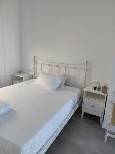 a bedroom with a white bed and two night stands at Almiriki- Ground Floor Seafront Studio in Elafonisos