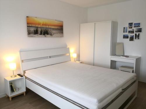 a white bedroom with a white bed and two lamps at Seeschloss 34 in Dahme