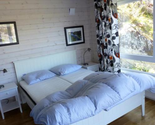 ein Bett mit blauen Kissen in einem Schlafzimmer mit Fenster in der Unterkunft Hagland Lille in Hagland