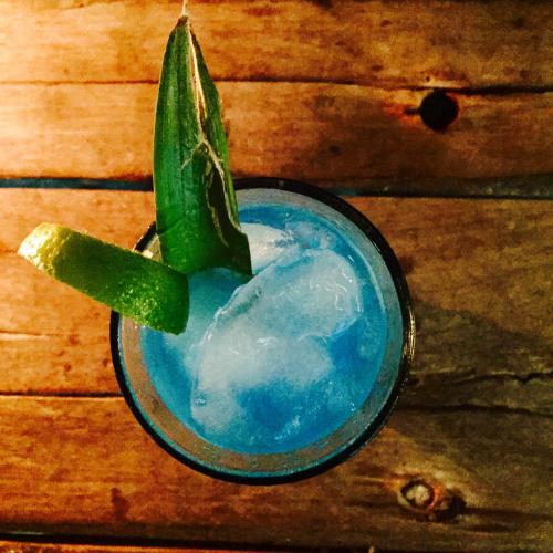 a blue drink with a green leaf on a wooden table at Zanzistar Lodge in Jambiani