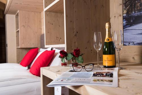 Una botella de champán y copas en una mesa de un dormitorio en Francesin Active Hotel, en Livigno