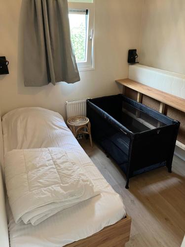 a bedroom with a bed and a desk and a window at Chalet 't Zwaluwnest in Aagtekerke