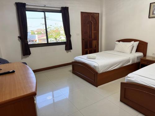 a bedroom with two beds and a desk and a window at Panchan Place in Ubon Ratchathani