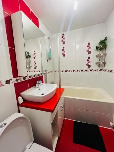 a red and white bathroom with a sink and a tub at Middeltown rose in Alba Iulia