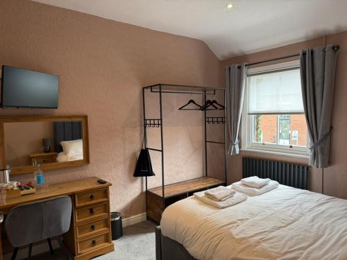 a bedroom with a bed and a desk and a window at The Applewood Regency in Southwell