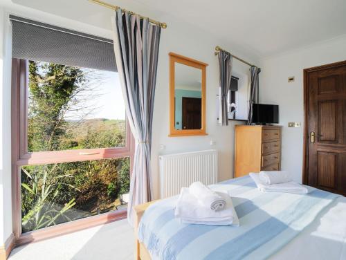 a bedroom with a bed and a large window at Sycamore in Penpillick