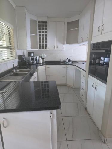 a kitchen with white cabinets and a black counter top at House 55D in Lichtenburg