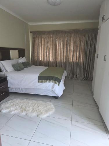 a bedroom with a bed and a window with a rug at House 55D in Lichtenburg