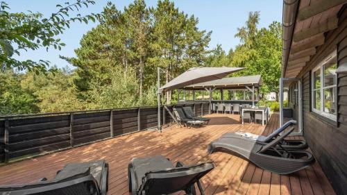 a deck with chairs and an umbrella on a house at Villavilla 247 - Ebeltoft, Østjylland in Ebeltoft