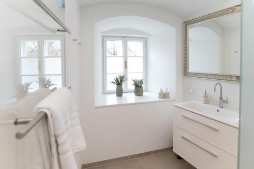 a white bathroom with a sink and two windows at GansFein Suites in Wels