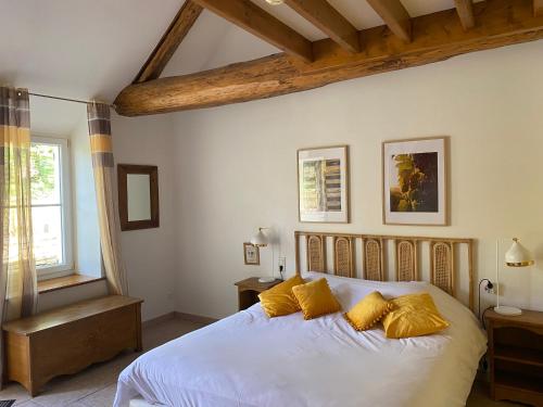 a bedroom with a white bed with yellow pillows at LE GOLURET Chambres & Table d'hôtes - Espace Bien Être in Couvignon