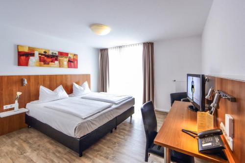 a hotel room with a bed and a desk with a computer at Ratshotel - City Aparthotel Aalen in Aalen