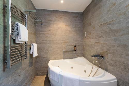 a white tub in a bathroom with stone walls at Forte Rose Hotel in Herceg-Novi