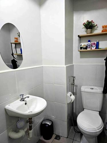 a bathroom with a white toilet and a sink at Cozy Plumera Studio near Mactan Airport in Bankal