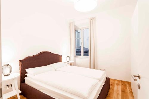 a bedroom with a bed with white sheets and a window at Stay COOPER l Laubenhaus in Bolzano