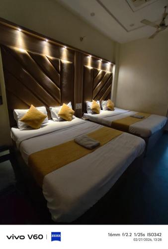 two beds in a hotel room with yellow pillows at HR King HOTEL in Amritsar