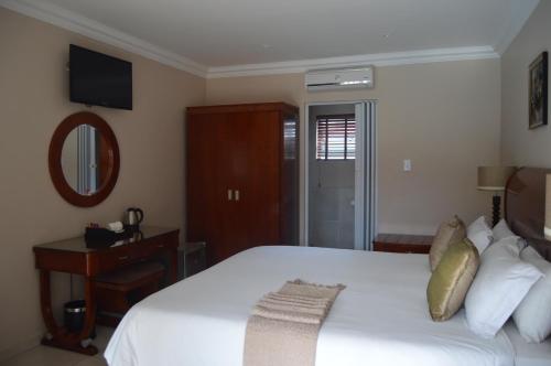 a bedroom with a large white bed and a mirror at Lakeview Boutique Hotel & Conference Center in Benoni