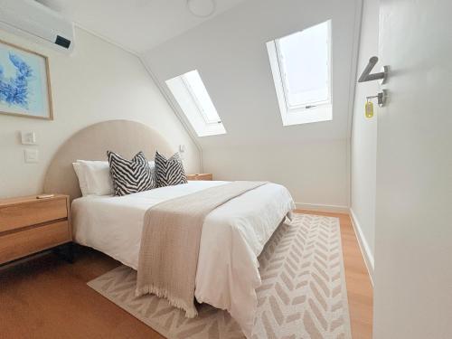 a white bedroom with a bed with two pillows at Little Acorn in Hermanus
